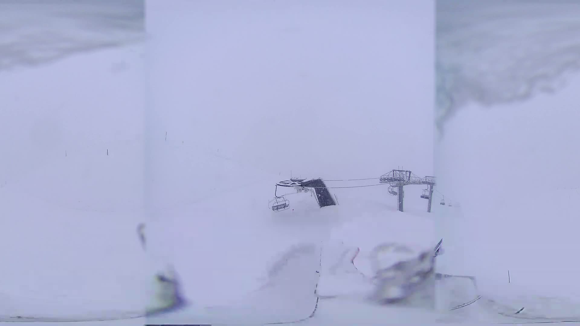 A snow-covered ski lift is visible in a heavy snowstorm.