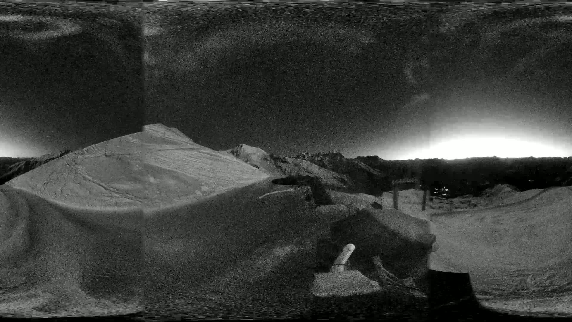A nighttime, snowy mountain landscape is shown, with a bright horizon indicating either sunrise or sunset.