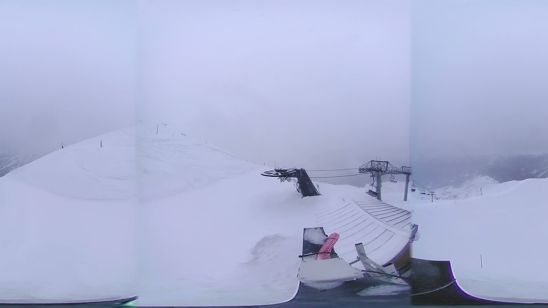 A snow-covered ski slope with a chairlift and snow removal equipment is visible under foggy conditions.