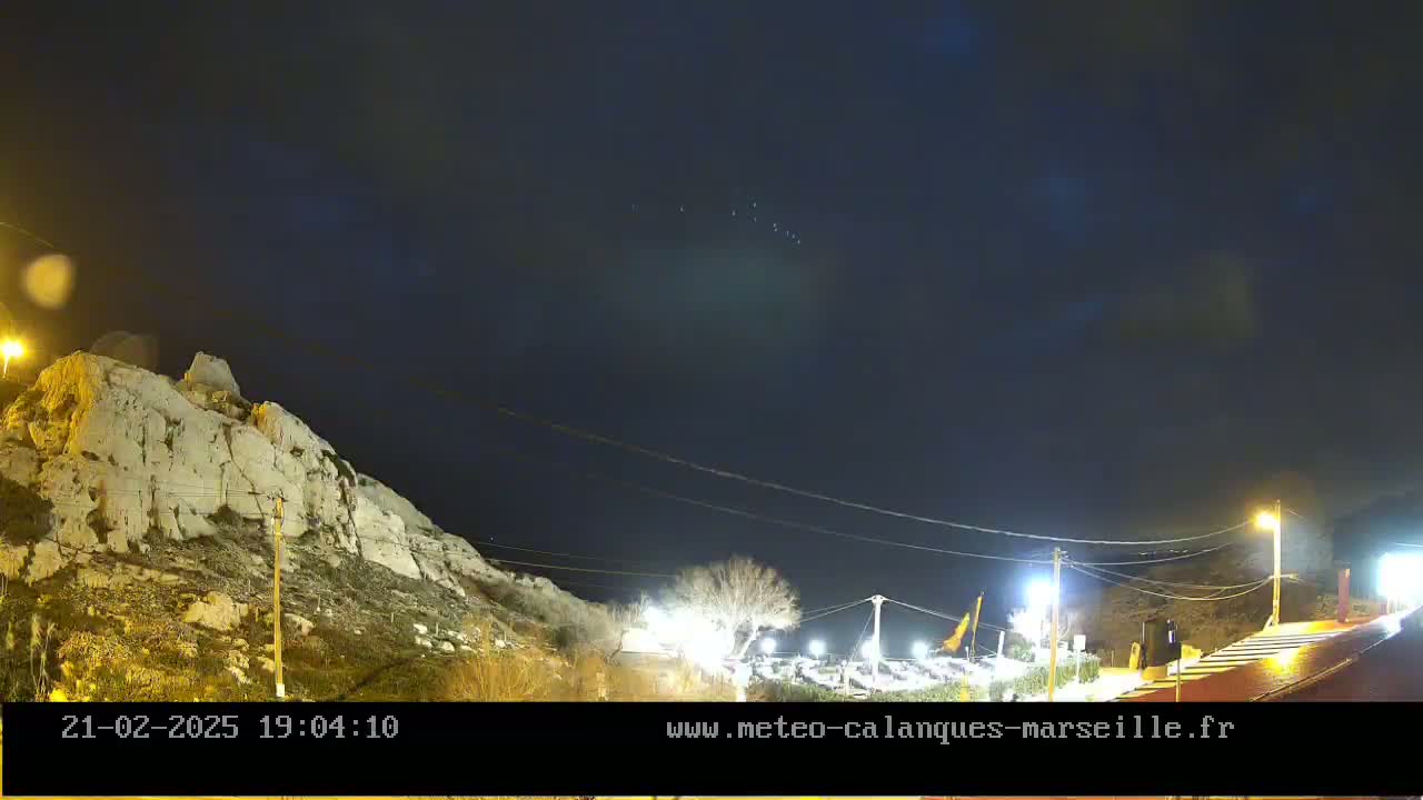 A nighttime view of a rocky hillside illuminated by artificial lights under a clear, dark sky.