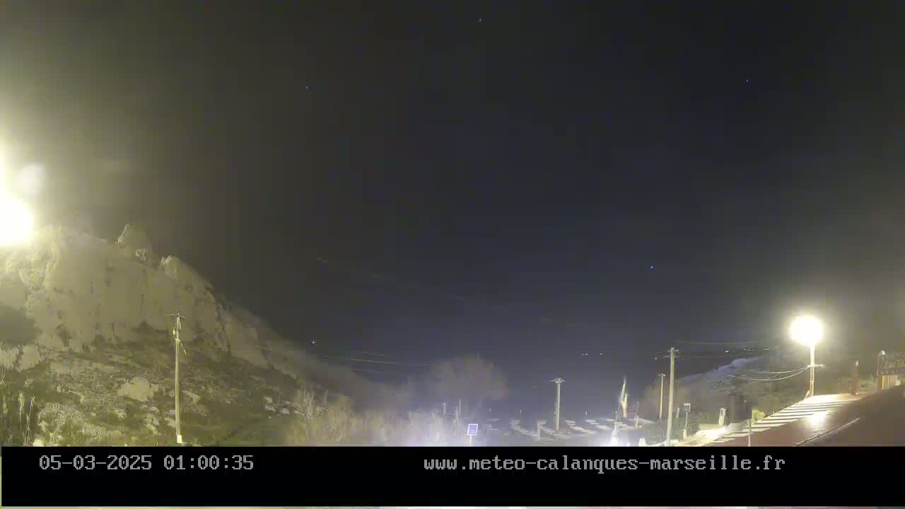 A nighttime view of a rocky hillside under a clear, dark sky illuminated by artificial lights.