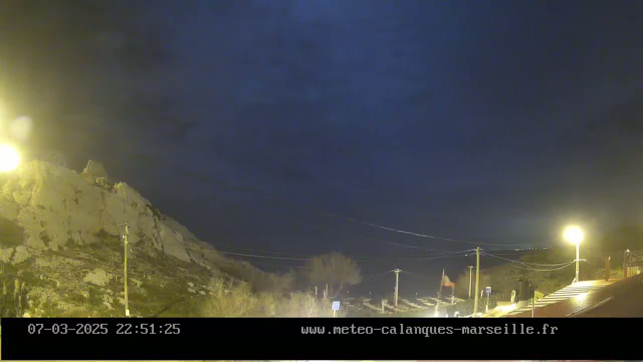 A nighttime view of a rocky hillside illuminated by streetlights under a dark, clear sky.