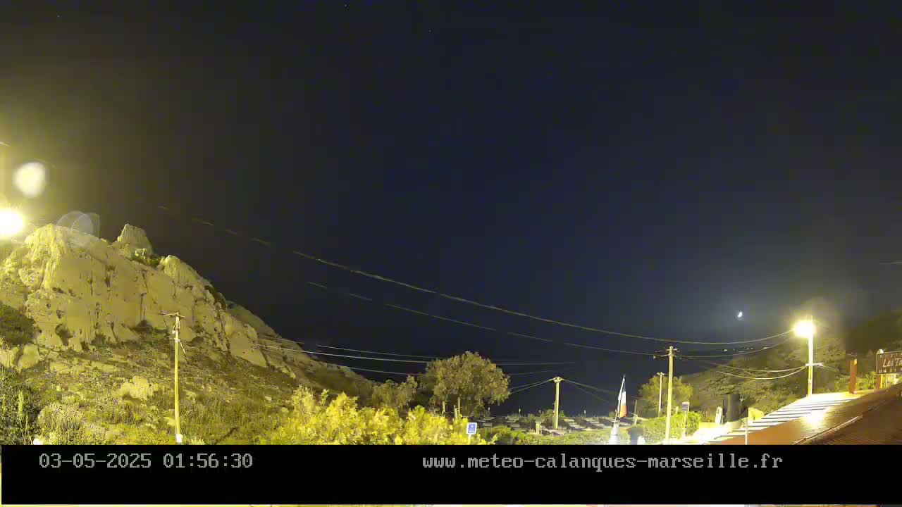 A nighttime view of a rocky hillside illuminated by artificial lights under a clear, dark sky.