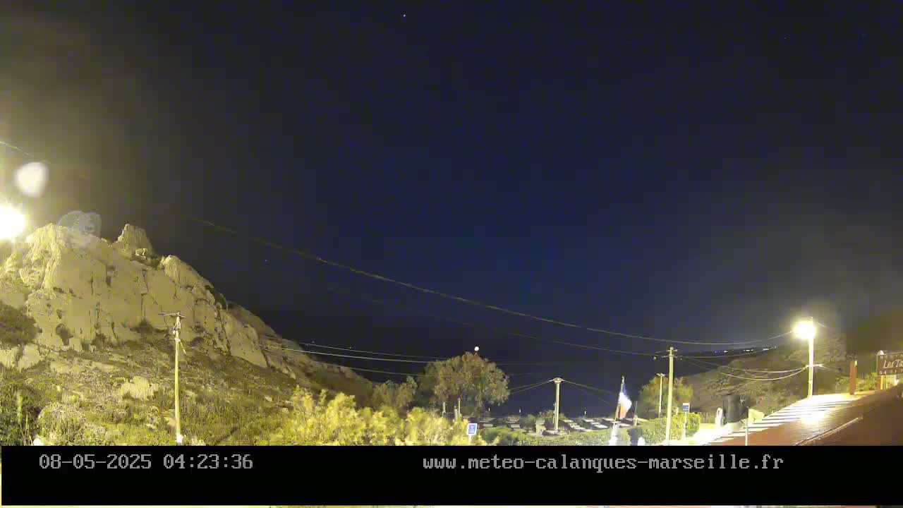 A nighttime view of a rocky hillside illuminated by streetlights under a clear, dark sky.