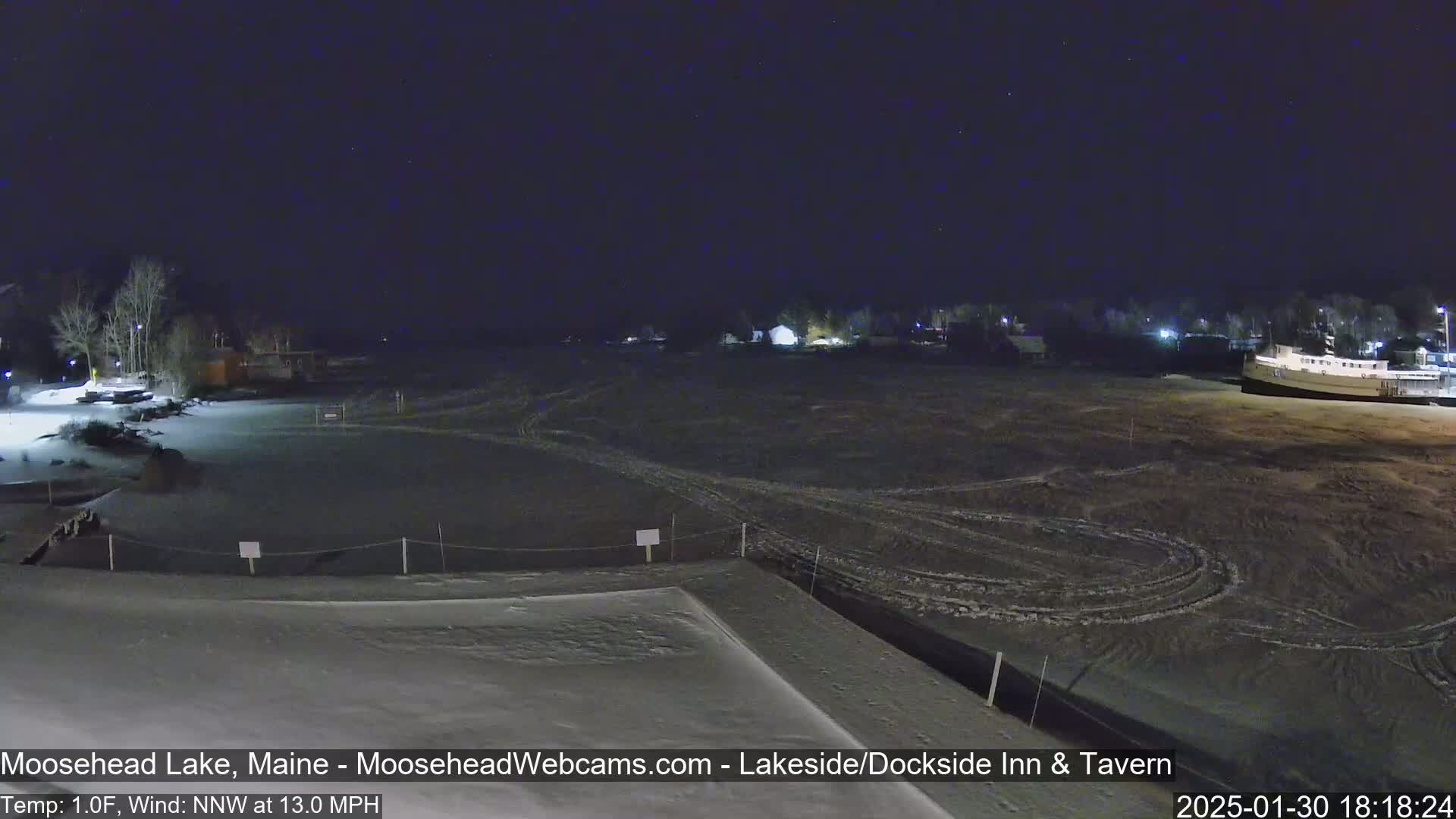 A snow-covered lakeside area at night under a dark, starry sky with a 1°F temperature and a 13 mph northwest wind.