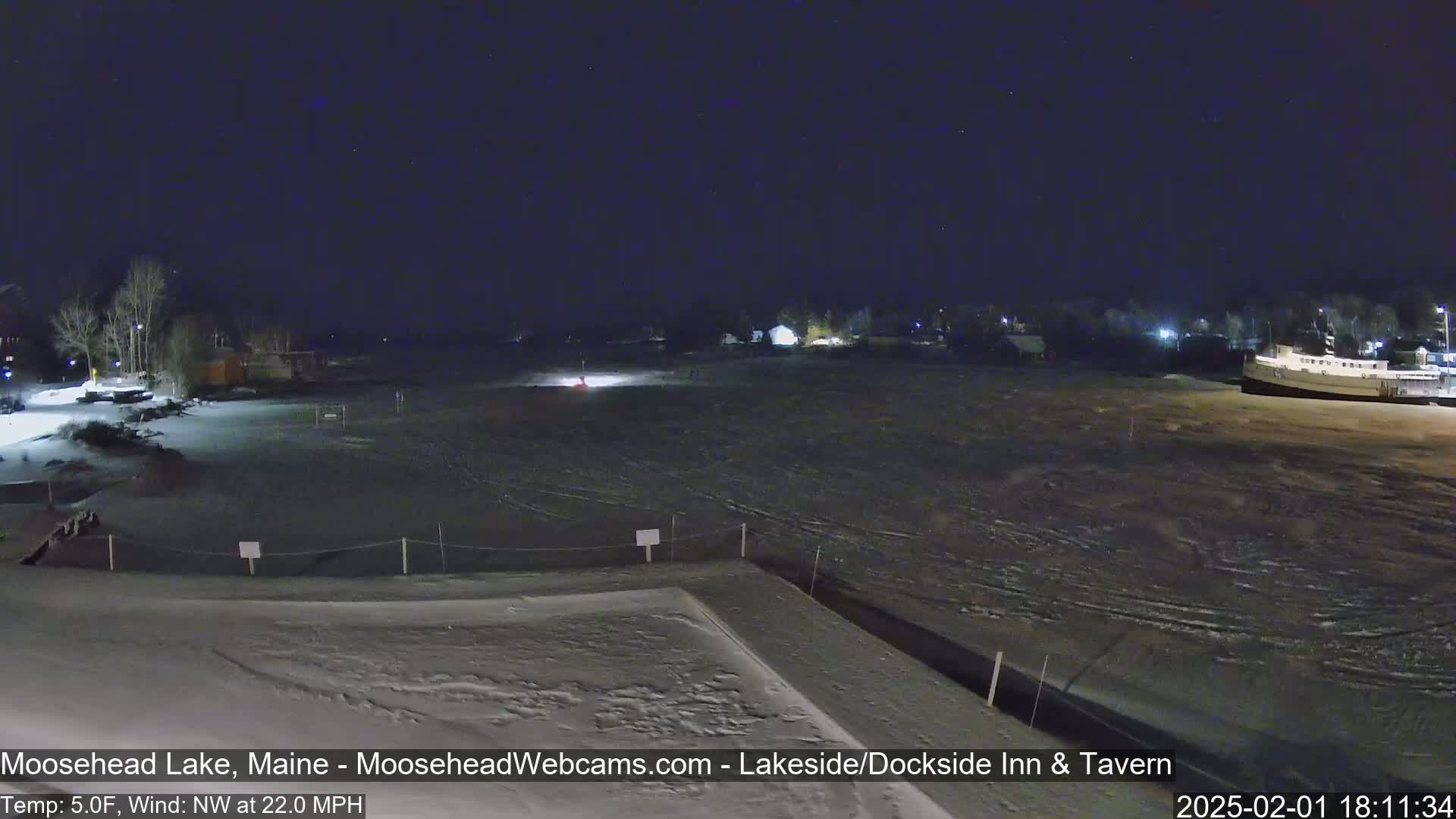 A snow-covered lakeside area is visible at night under a dark, starry sky, with a northwest wind blowing at 22 mph and a temperature of 5 degrees Fahrenheit.