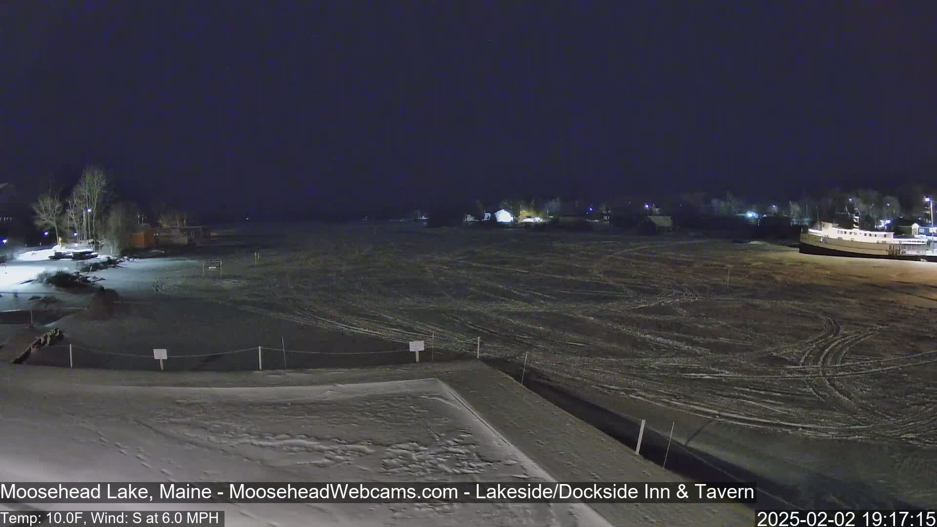 A snow-covered lakeside area at night, with a calm wind and a temperature of 10°F.