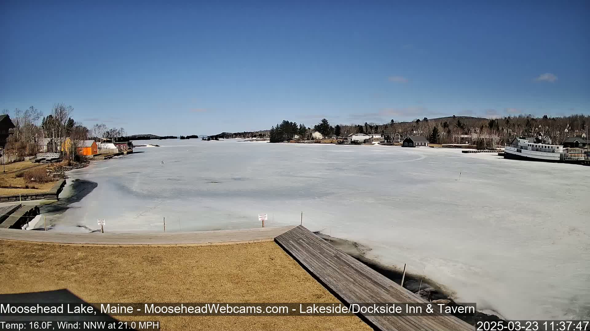 A partially frozen lake is seen from a lakeside dock on a sunny day with a  north-northwest wind.