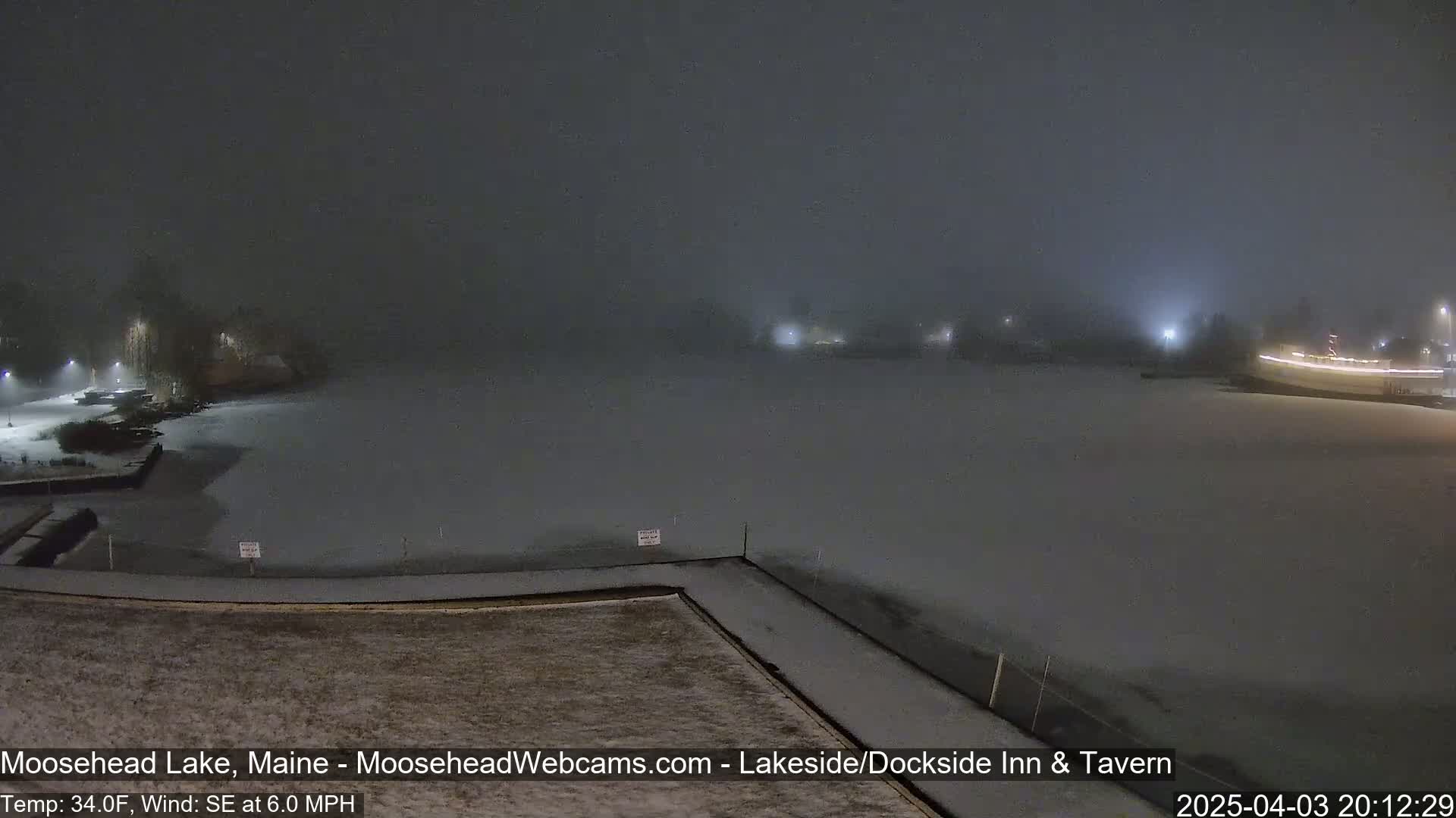 A snow-covered lake is seen at night in foggy conditions.