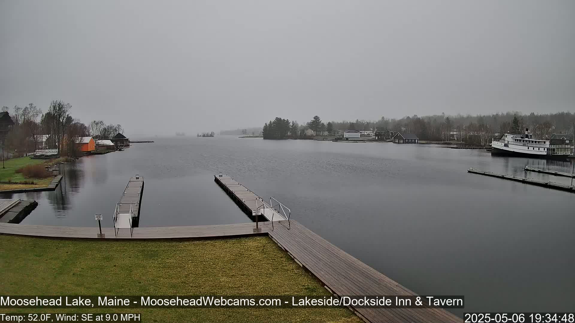 A lake with several docks and buildings on the shore is shown under an overcast sky, with a slight southeast wind.