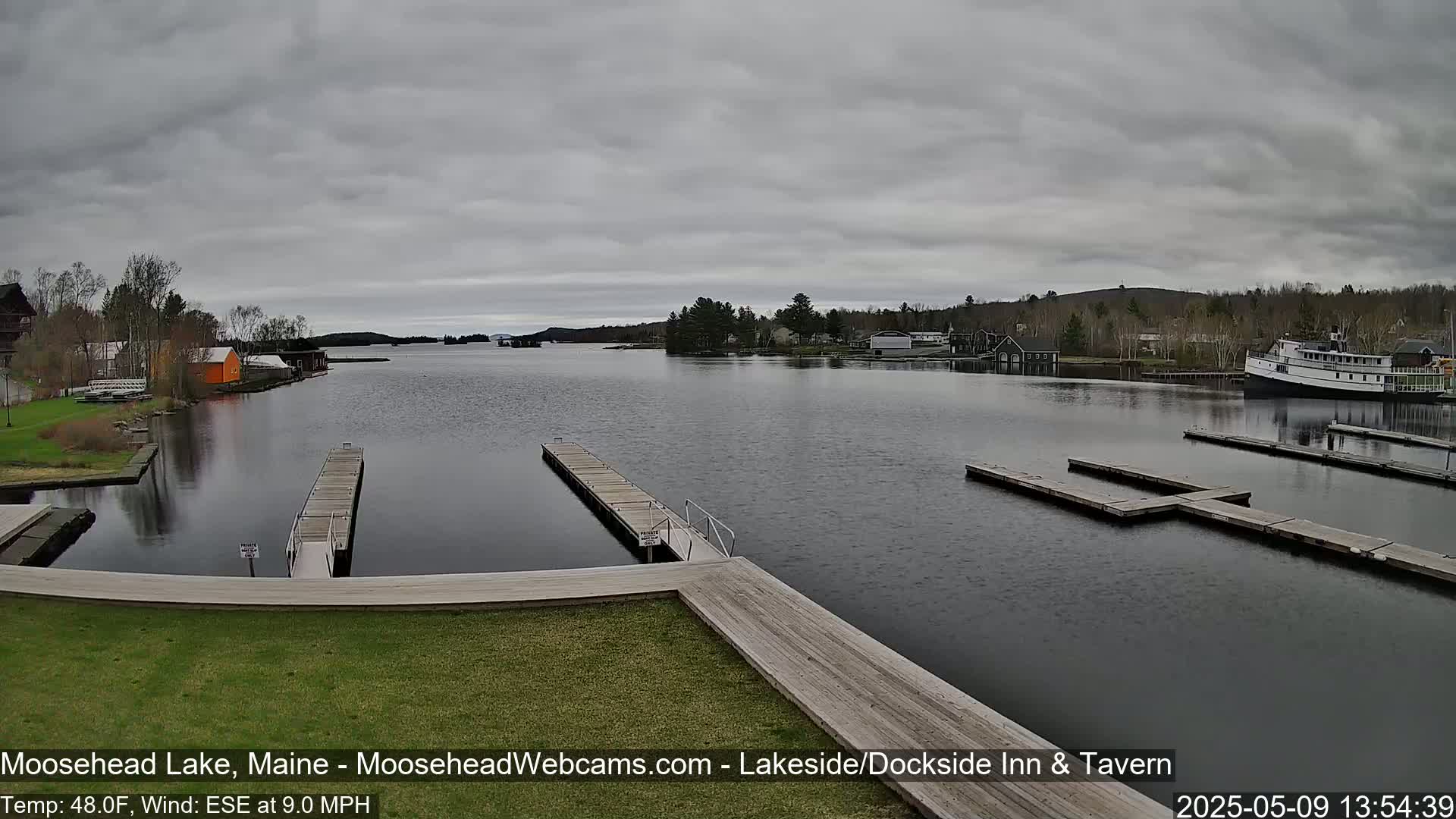 A calm lake with several docks and a large boat is visible under an overcast sky.