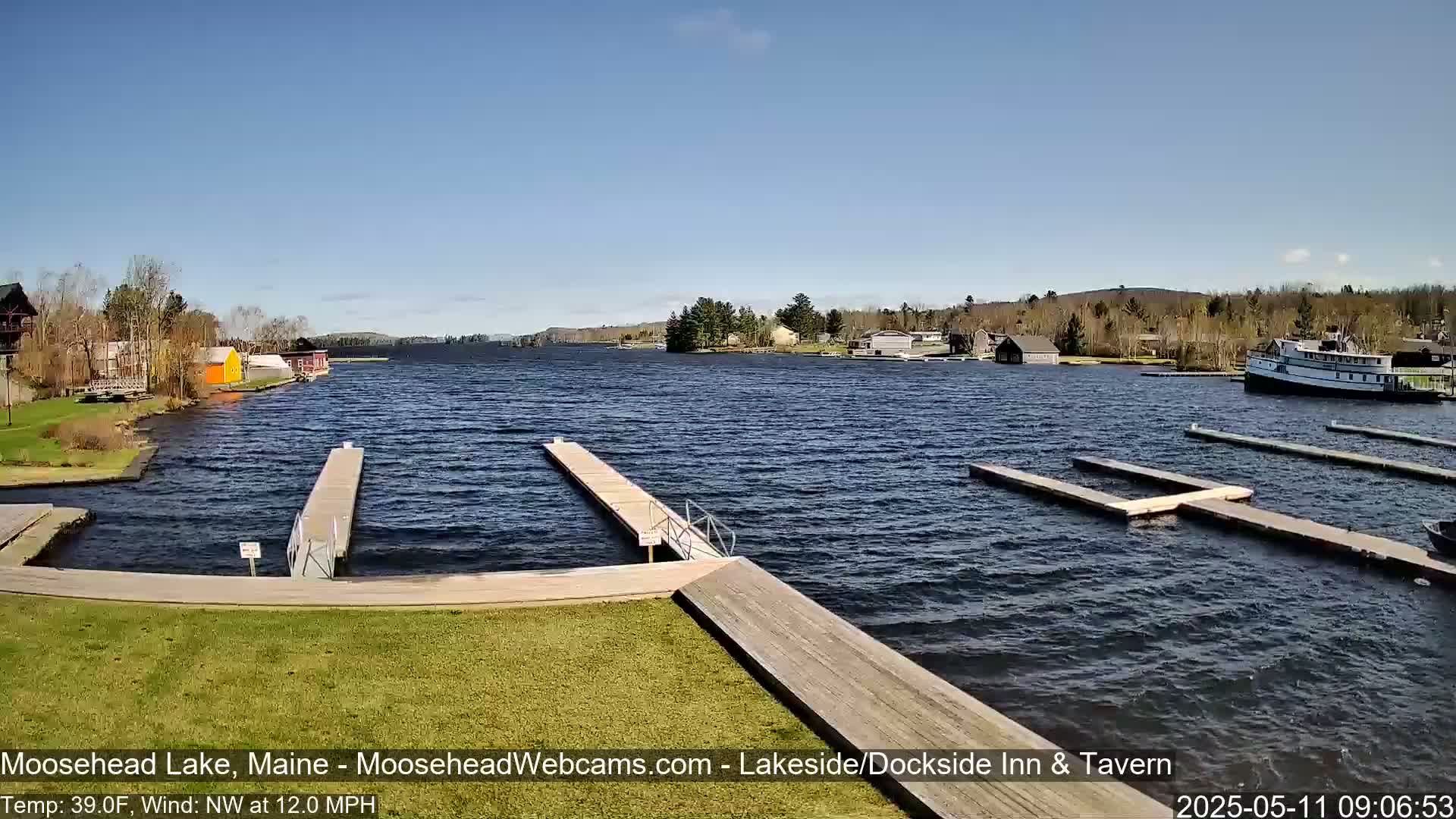 A lake with several docks and a boat is visible under a clear blue sky with a moderate northwest wind.