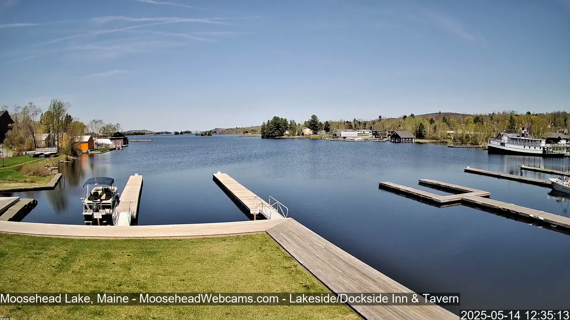 A calm lake with several docks and boats, under a clear blue sky, on a sunny day.