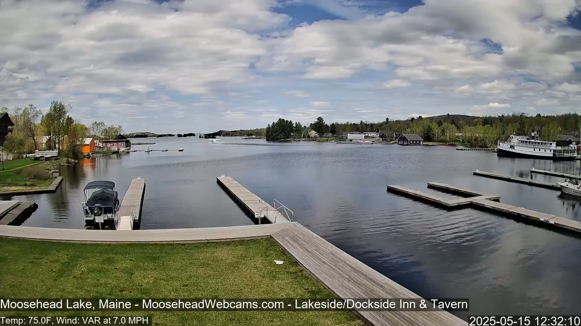 A calm lake with numerous docks, boats, and buildings is visible under a partly cloudy sky.