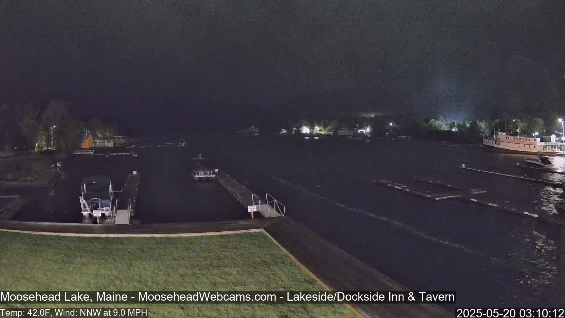 At night, under a dark sky with a 9 mph northwest wind and a temperature of 42°F, boats are moored at docks on a calm lake.