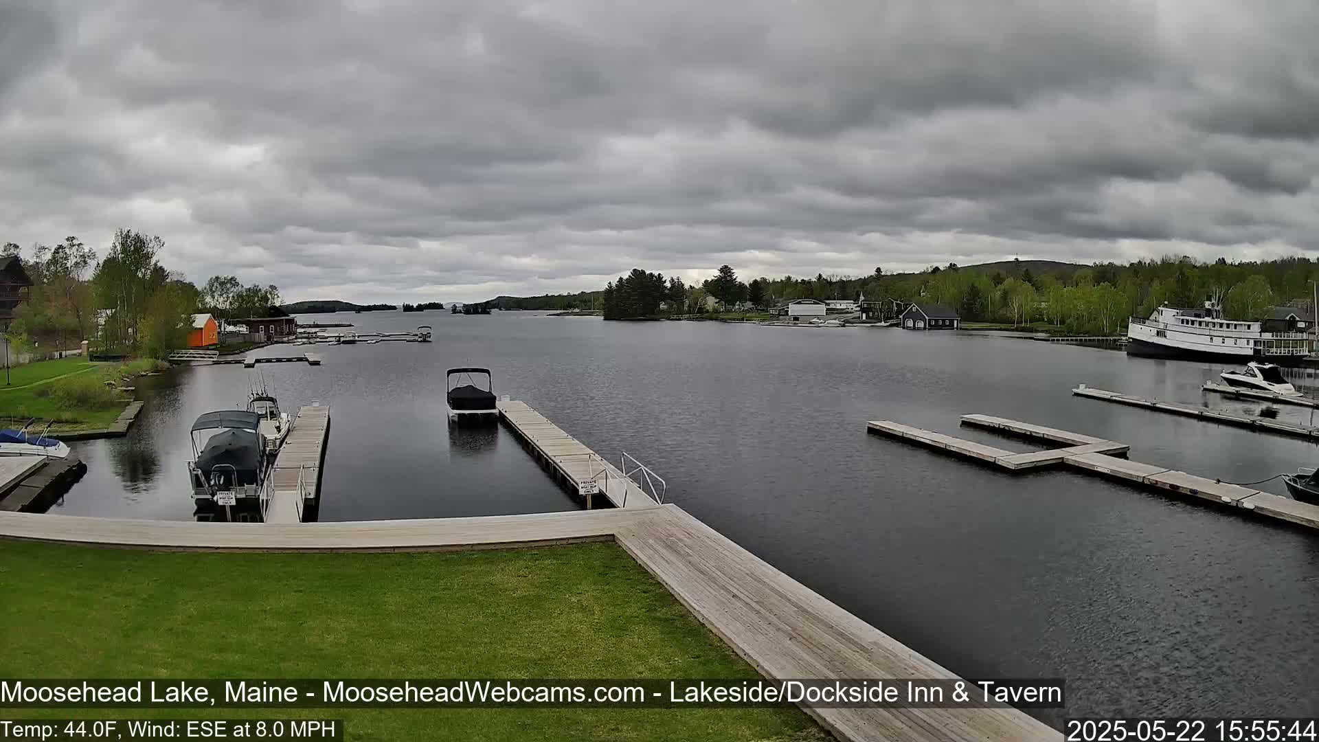 A lake with several boats docked at piers, under a cloudy sky.