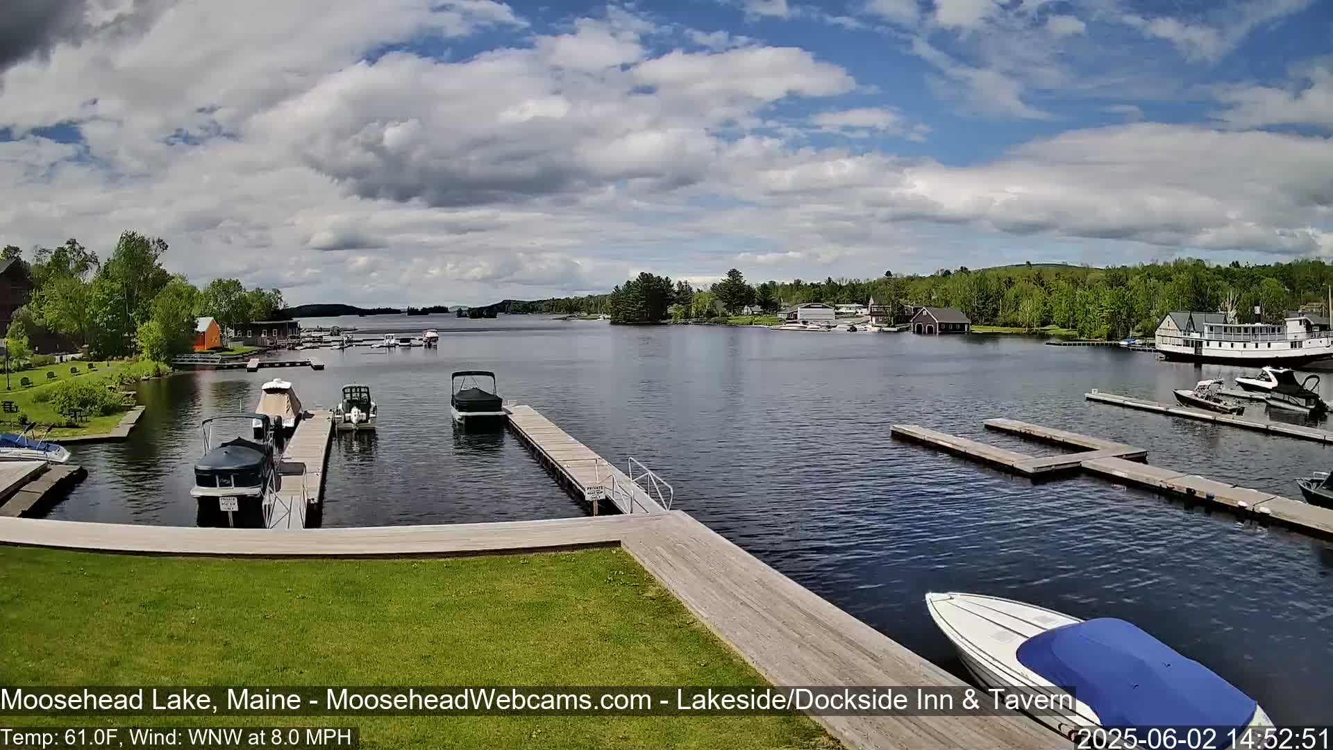 A calm lake with numerous boats docked at piers, under a partly cloudy sky.