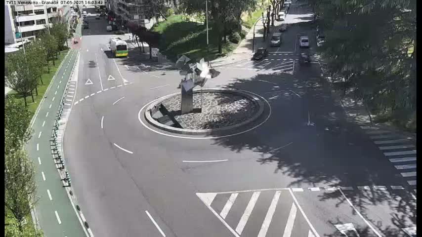 A roundabout with a modern sculpture in the center, surrounded by roads and bike lanes, on a sunny day.