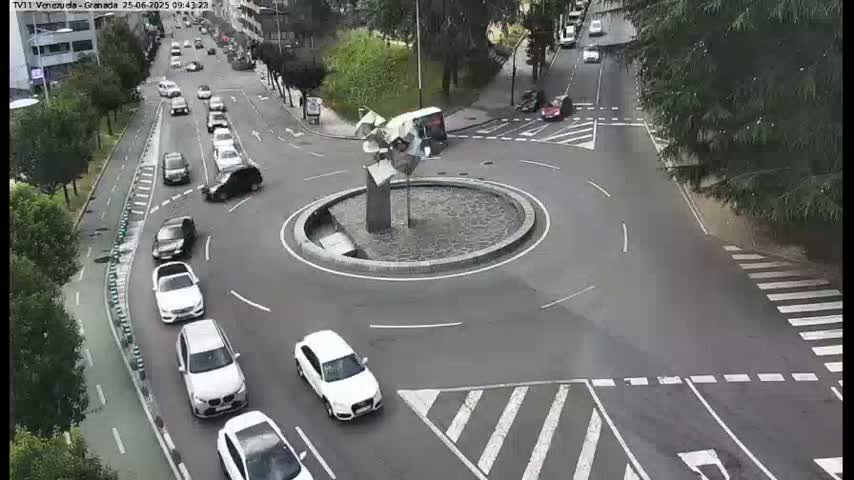A roundabout with several cars in and around it on a sunny day.