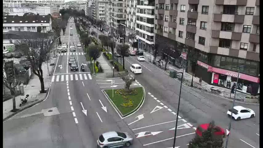 A street intersection with several cars and buildings on a cloudy day.