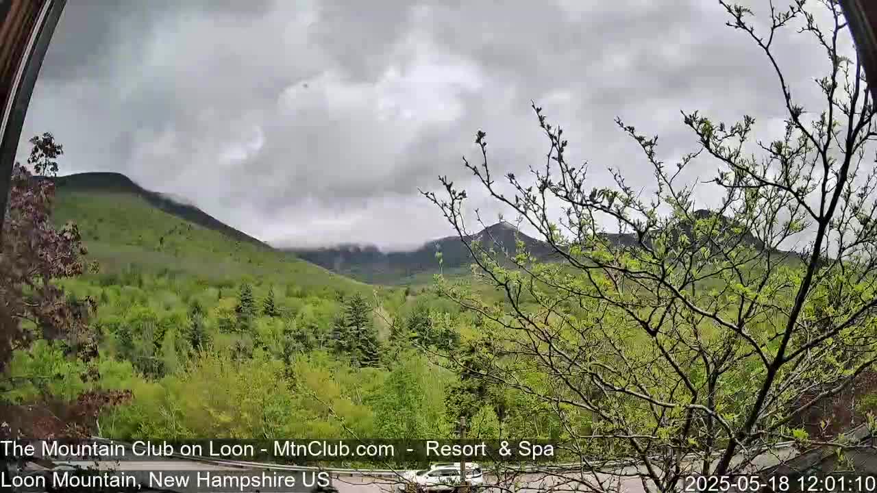 A view of lush green mountains partially shrouded in clouds under an overcast sky.