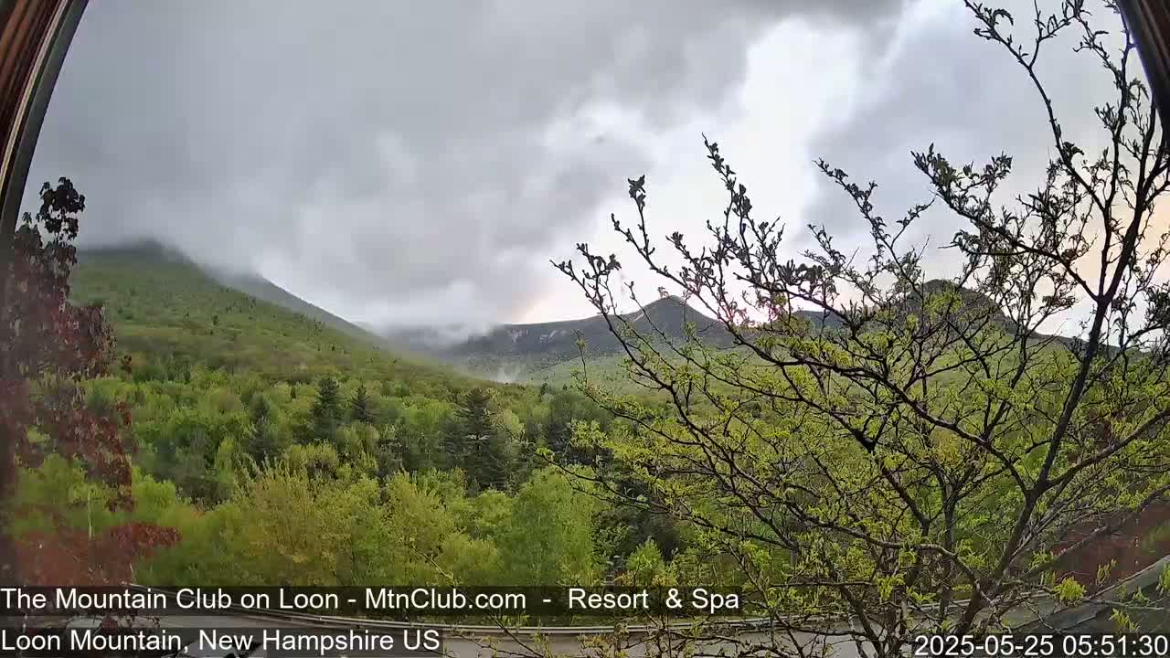 A view of lush green mountains partially obscured by a cloudy sky.