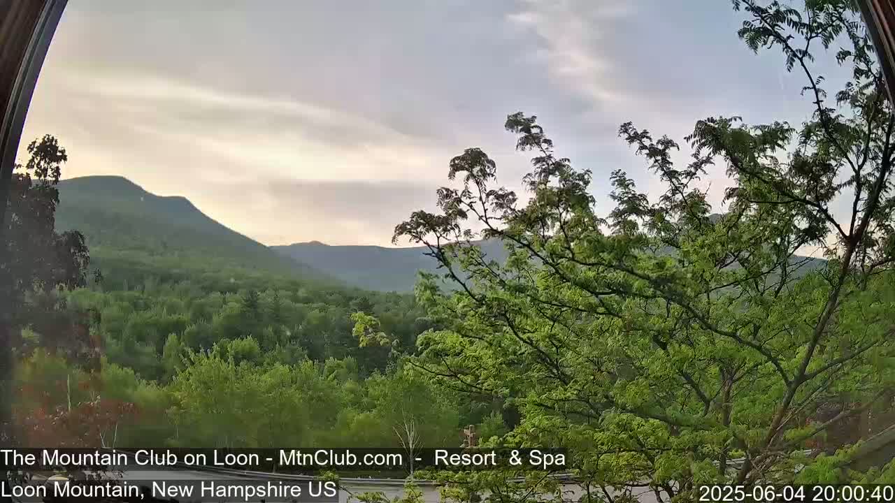 A view through an arched window shows a mountainous landscape under a partly cloudy, twilight sky.