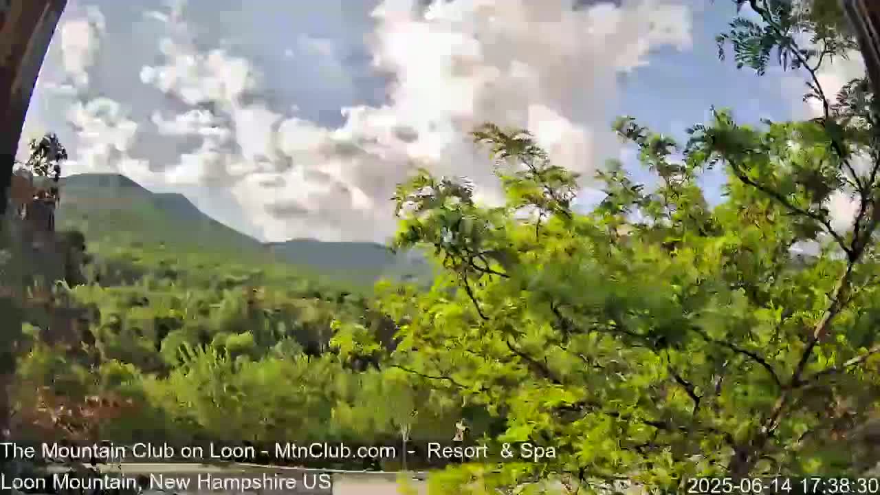 A view through an arched window shows a lush green mountain range under an overcast sky.