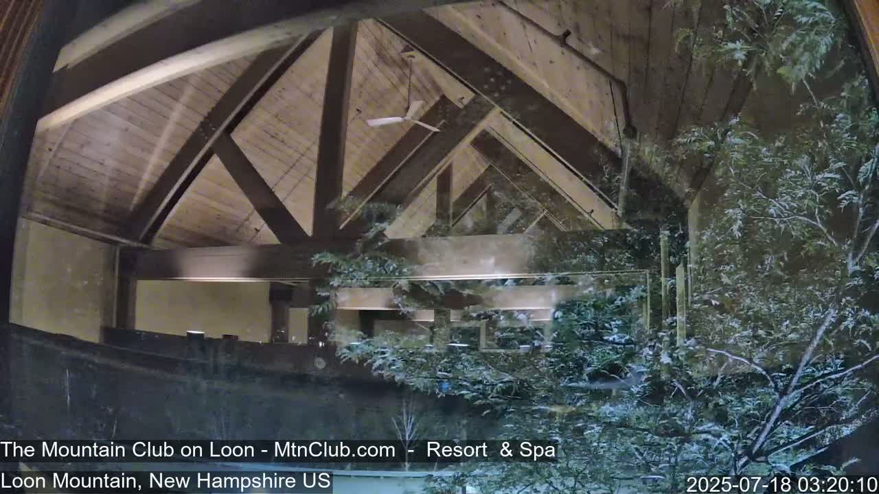 A view through a window shows a wooden-beamed interior ceiling and a snow-covered landscape outside at night.