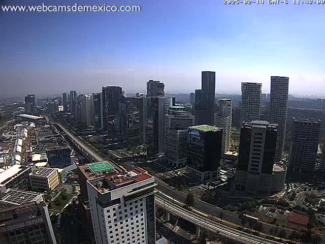 A high-angle, long shot on a clear day shows a city skyline with numerous skyscrapers and a large highway running through it.