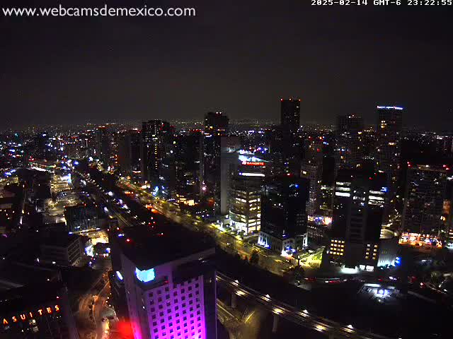 A nighttime, aerial view of a city with numerous skyscrapers and brightly lit roads and highways under a clear, dark sky.