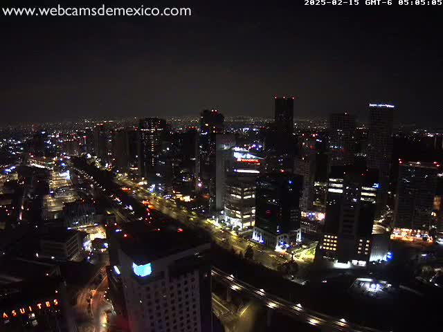A nighttime aerial view of a city, showing illuminated buildings and roads under a clear, dark sky.