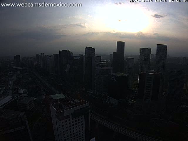 A hazy sunrise illuminates a cityscape of dark, tall buildings and a highway below.