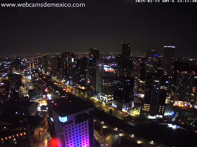 A nighttime aerial view of a city with many illuminated buildings and roads under a clear sky.
