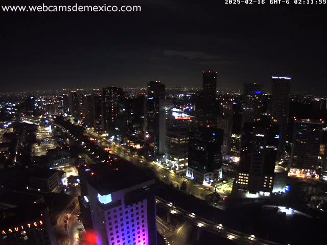 A nighttime aerial view of a city with illuminated buildings and roads under a mostly clear sky.