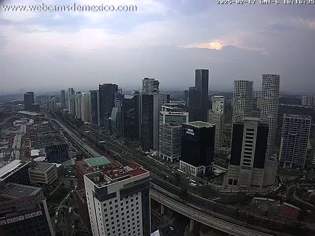 A sprawling cityscape of tall, dark buildings under a cloudy sky.