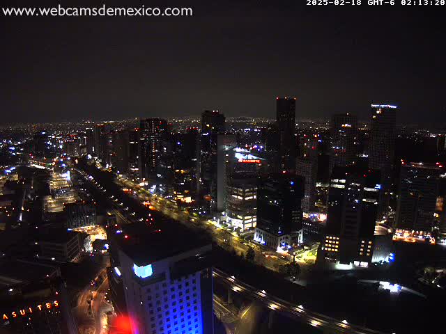 A nighttime aerial view of a city with illuminated buildings and roadways under a clear, dark sky.