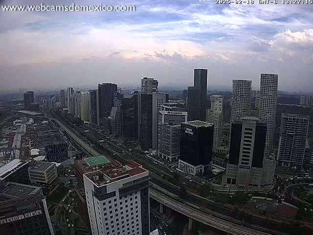 A cityscape of numerous high-rise buildings under a partly cloudy sky.
