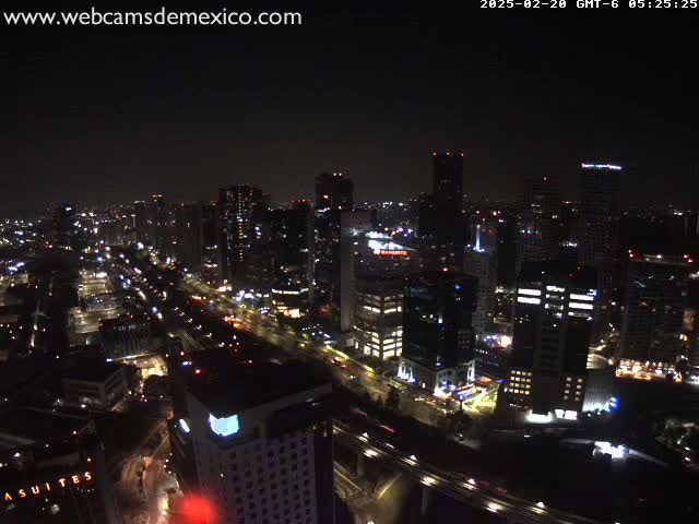 A nighttime aerial view of a city with numerous illuminated skyscrapers and roadways.