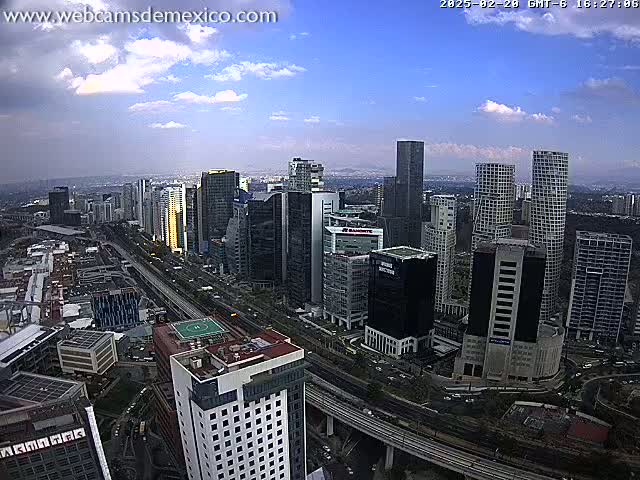 A partly cloudy day reveals a cityscape of numerous skyscrapers and high-rise buildings, with a highway weaving through the lower levels.