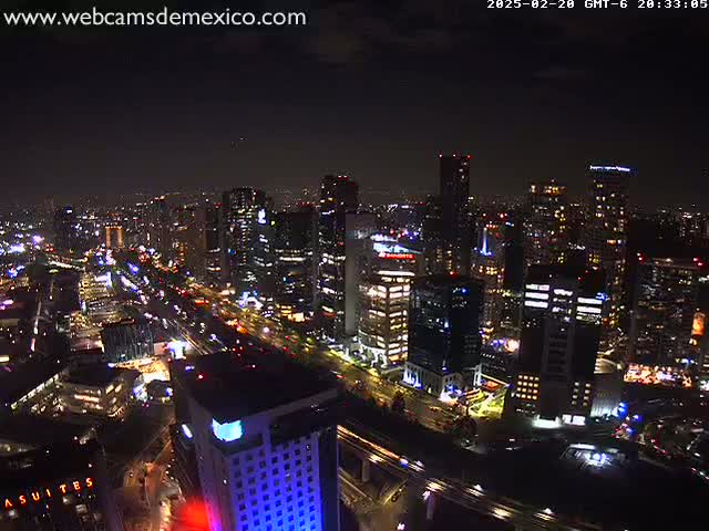 A nighttime aerial view of a city skyline with brightly lit buildings and roads, under a clear, dark sky.