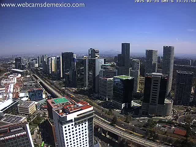 A sprawling cityscape of tall buildings under a clear, bright blue sky.