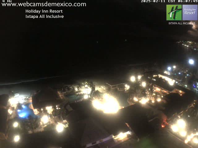 A brightly lit resort at night, situated on a coastline under a dark, clear sky.