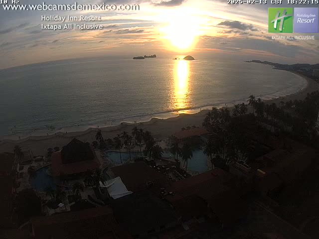 A coastal resort at sunset, with a beach and ocean visible under a partly cloudy sky.
