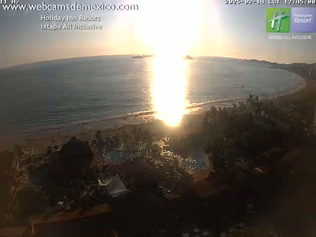 A beach resort at sunset, with the sun reflecting brightly off the ocean.