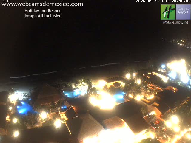 A brightly lit resort at night, situated on a beach under a clear, dark sky.