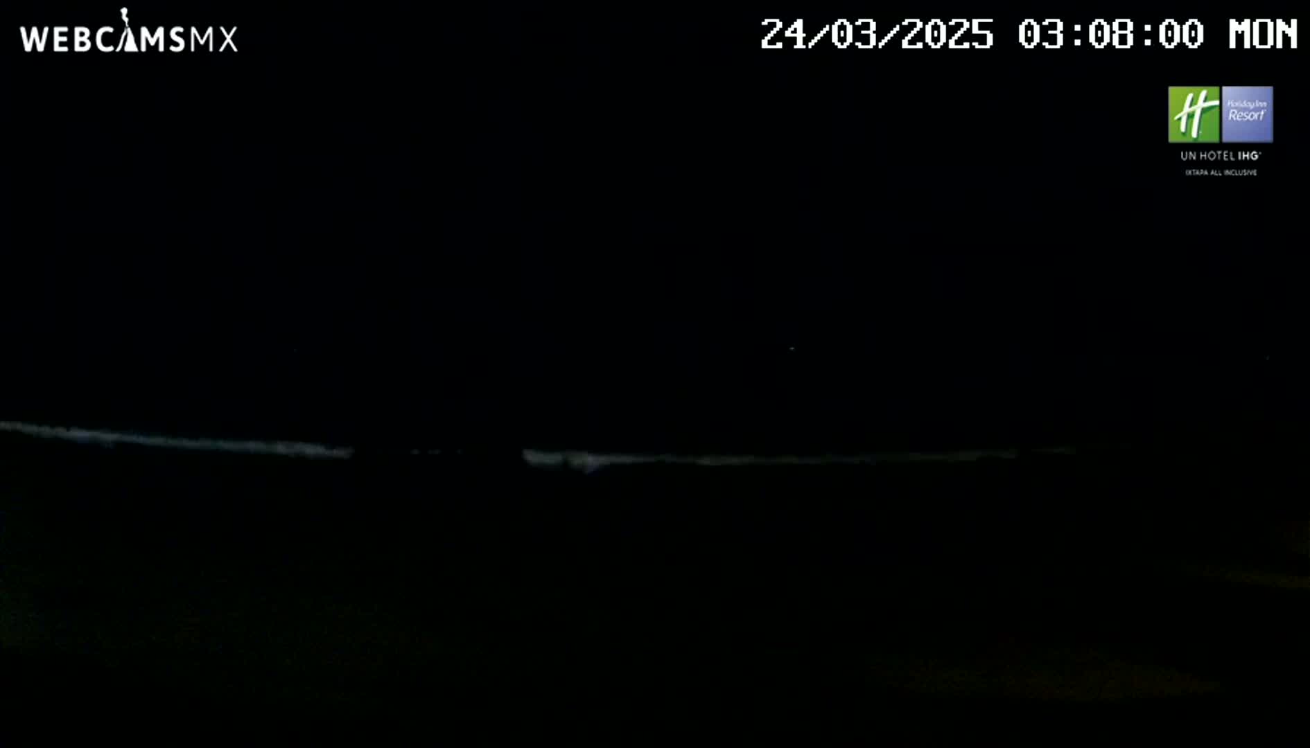A dark, nighttime scene shows a faintly illuminated horizon line, possibly representing the ocean under a clear sky.