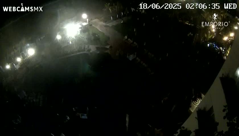 A nighttime aerial view shows a dark pool and surrounding landscaping illuminated by artificial lights.