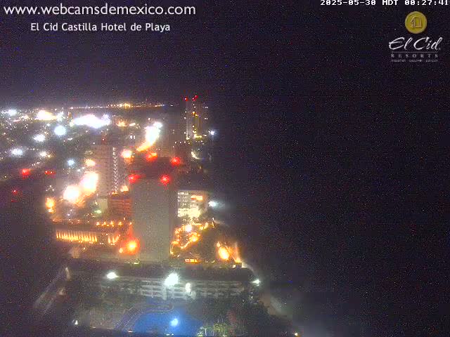 A brightly lit resort town at night, viewed from above, under a clear, dark sky.