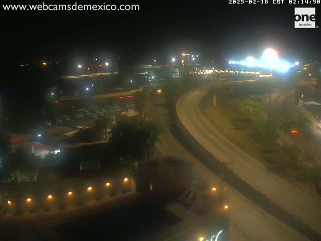 A nighttime, high-angle view of a highway interchange with sparse traffic, illuminated by streetlights and buildings.